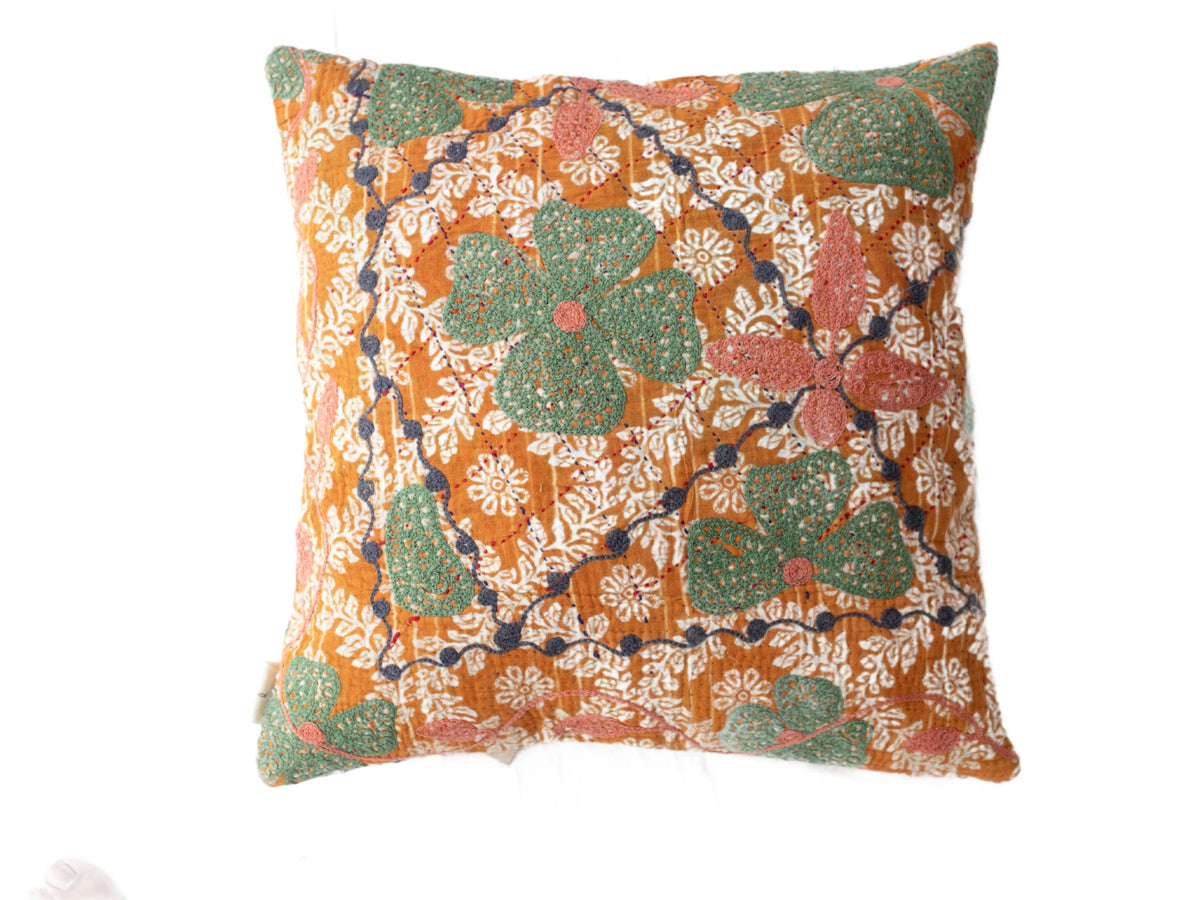 Suzani Kissenbezug im Boho-Vintage-Stil mit orangefarbenem Grundton und weißen floralen Ornamenten sowie großen grünen Blättern mit rosa Punkten und dunkelblauen Ranken.